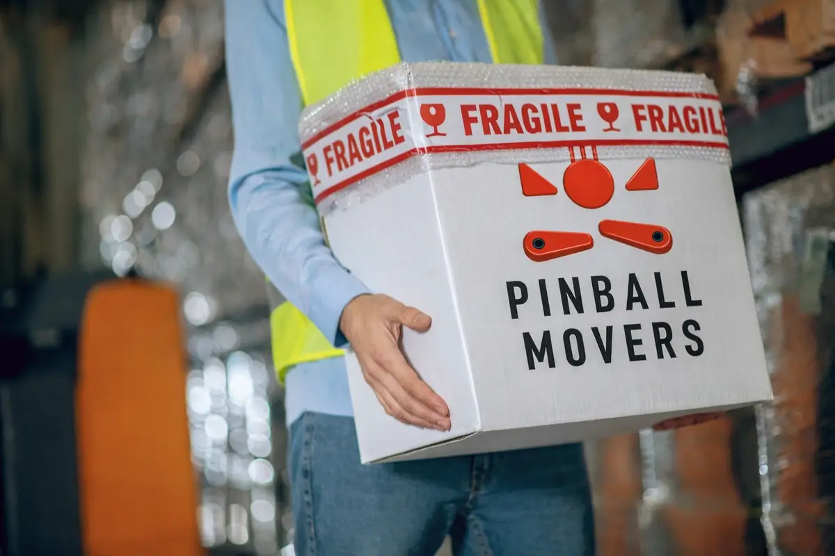 Pinball Movers handling a fragile box for specialist transport of delicate gaming equipment